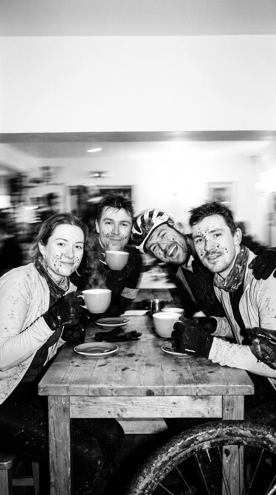 mud-splattered riders grinning round a café table