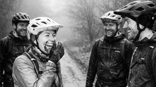 a rider in fits of laughter with three mates on a muddy forest track