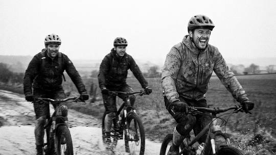 three riders laughing as they splash through a big puddle